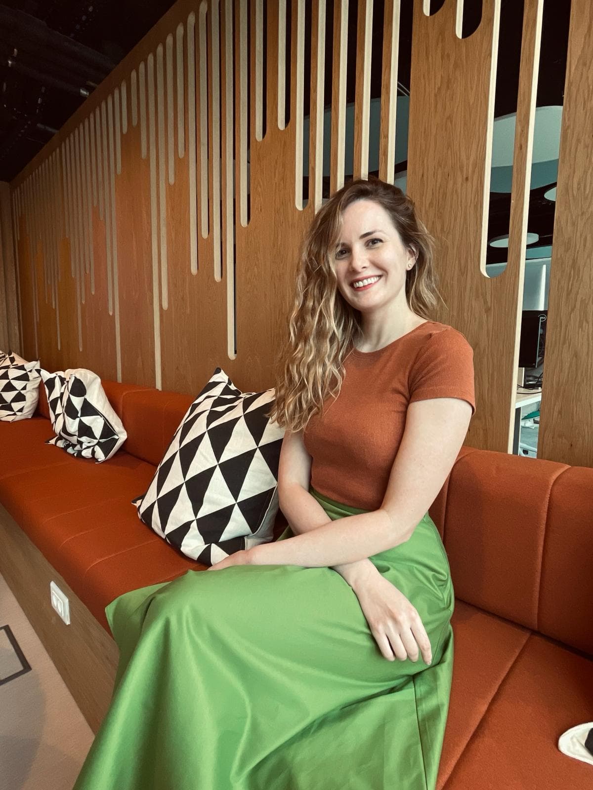 Nikolina Momcilovic, holistic career coach, smiling and sitting in a modern space.